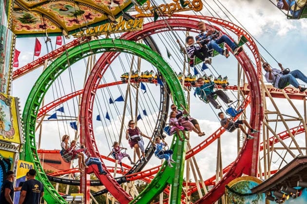 Abschied von der Wiesn, Wiesnbesucher fliegen im Kettenkarussell Wiellenflug durch den bayerischen Himmel, während dahinter Besucher eine wilde Runde im Olympia-Looping drehen, Sonntagnachmittag, München, 4. Oktober 2026 Deutschland, München, 4. Oktober 2026, letzter Tag des Oktoberfests 2026, Abschied von der Wiesn, Wiesnbesucher fliegen im Kettenkarussell Wiellenflug durch den bayerischen Himmel, während dahinter die Fahrgäste im Olympia-Looping eine wilde Runde drehen, Sonntagnachmittag, Wechsel von Sonne und Wolken, schönes Wiesnwetter, Ende einer Rekord-Wiesn mit 7,4 Millionen Besuchern, Wochenende, typisch bayerisch, Volksfest, Bayern,