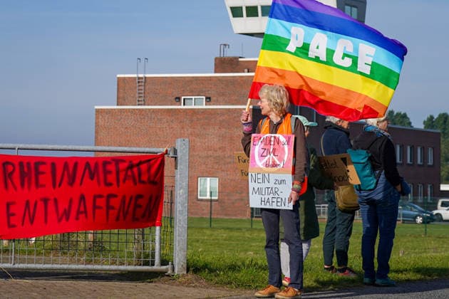 Protest in Emden vor dem Hintergrund der heutigen Pressekonferenz zur geplanten militärischen Nutzung des Emder Hafens. Demonstrantin mit PACE-Friedensfahne und Schildern Emden soll zivil bleiben! und Nein zum Militärhafen!. Bundeswehr, Boris Pistorius, Verteidigungsminister, Militär, Marine, NATO, Hafen, kritische Infrastruktur, Rüstung, Friedensbewegung, Demonstration, Emden, Niedersachsen. Copyright: xJOERANxSTEINSIEKx