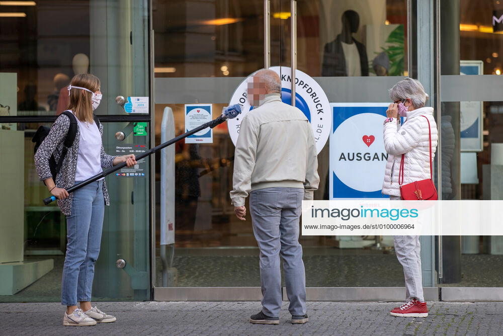 Wuerzburg, City, 27.04.2020, Coronavirus: Teiloeffnung der Wuerzburger Woehrl Filiale Bild: Eine TV Reporterin interviewt Personen vor der Oeffnung der Wuerzbuger Woehrl Filiale. Woehrl erreicht Teiloeffnung von Standorten über das Verwaltungsgericht, die Verkaufsflächen muessen auf maximal 800 Quadratmetern begrenzt werden