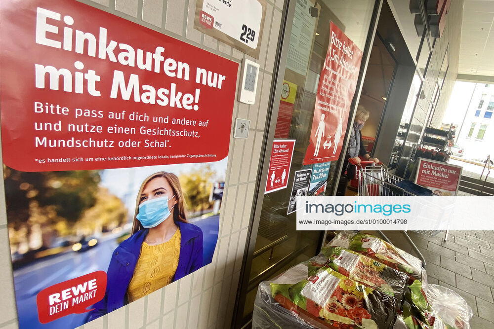 Lockerungen und Maskenpflicht in der Coronavirus Pandemie: Geschaefte in Bayern oeffnen am 27.April wieder. Ein Schild weist auf das Tragen von Mund Nasenschutz hin.Maskenpflicht. REWE Supermarkt Ladengeschaeft ,Filiale,Eingang,