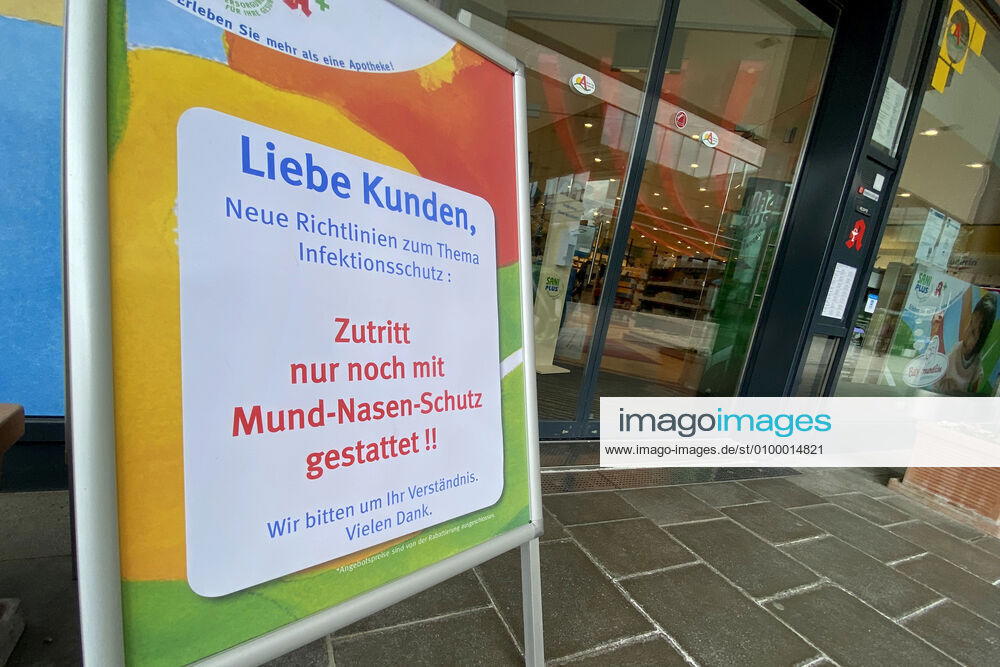 Lockerungen und Maskenpflicht in der Coronavirus Pandemie: Geschaefte in Bayern oeffnen am 27.April wieder. Hinweis,Aufsteller vor einer Sani Plus Apotheke: Zutritt nur noch mit Mund-Nasen-Schutz gestattet. Ladengeschaeft ,Filiale,Eingang,