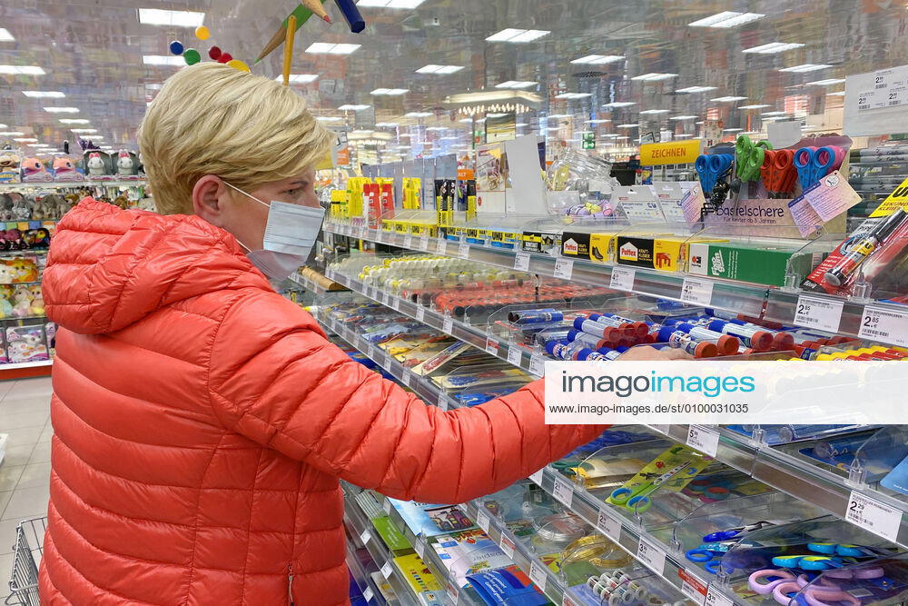 Lockerungen und Maskenpflicht in der Coronavirus Pandemie: Geschaefte in Bayern oeffnen am 27.April wieder. Eine Frau mit Mund-Nasen-Schutz in der Schreibwarenabteilung in einem Drogeriemarkt . Ladengeschaeft ,Filiale,Eingang,