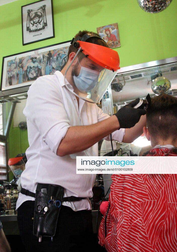 Belgrade(Serbia) Coronavirus Covid-19 Life loosening measures Friseur hair stylist studio Goca Gotza open after 43 days state of emergency.Friseour hairdresser Nikola working with protection mask,vizir visor made of plexiglass.