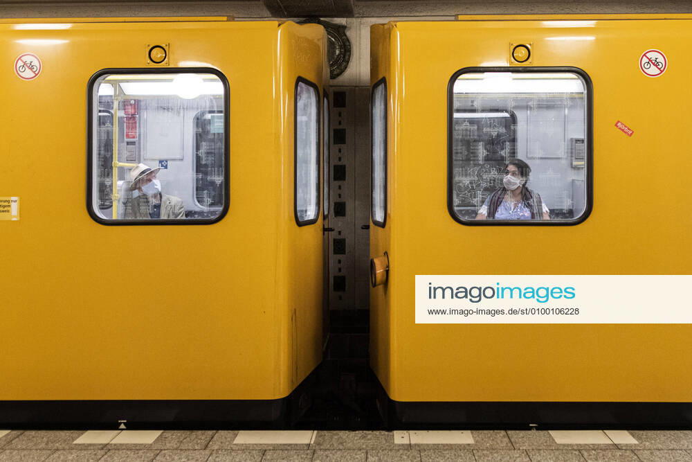 Zwei Personen mit Mund-Nasen-Maske sitzen in uterschiedlichen Waggons der U-Bahn in Berlin, 28.04.2020. Deutschlandweit gibt es eine Maskenpflicht im Oeffentlichen Personennahverkehr. Berlin Deutschland