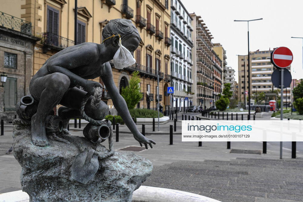 A protective mask is placed on a statue of a child fisherman, in street riviera, in Naples city. Government Decree declaring all of Italy a protected area to combat Covid-19 - Coronavirus infection.