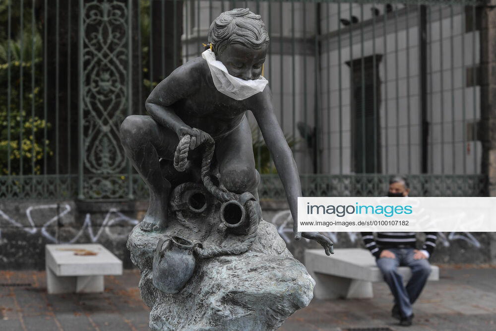 A protective mask is placed on a statue of a child fisherman, in street riviera, in Naples city. Government Decree declaring all of Italy a protected area to combat Covid-19 - Coronavirus infection.
