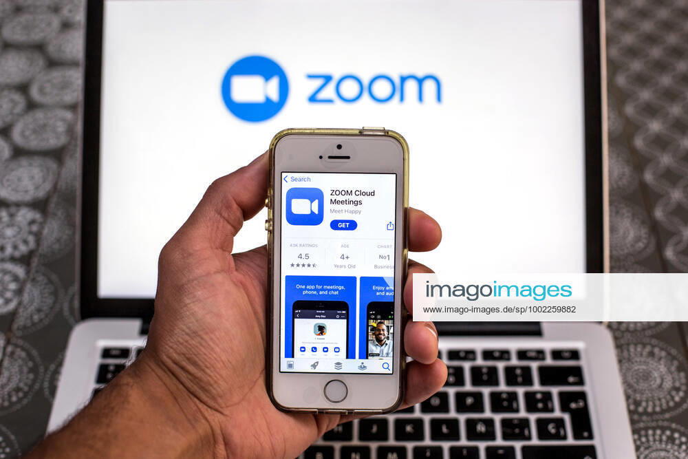 In this photo illustration, the Zoom app in App Store seen displayed on a smartphone screen and a Zoom logo on a laptop in the background. Barcelona Spain - ZUMAd159 20210420_zia_d159_094