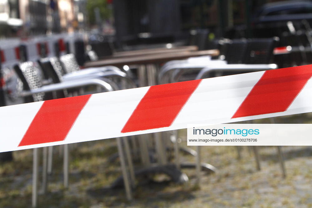 Absperrband um Tische und Stühle eines geschlossenen Restaurants in der Innenstadt von Mannheim, Baden Württemberg, Deutschland