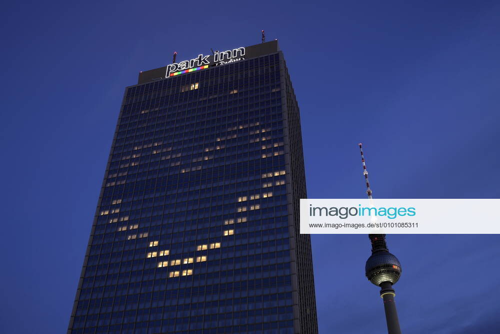 Berlin, Deutschland - Foto: Hotel Park Inn und der Fernsehturm am Alexanderplatz. Das Hotel Park Inn am Alexanderplatz hat waehrend der Corona-Krise einige Fenster so beleuchtet, dass sie zusammen ein Herz bilden.