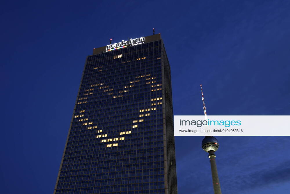 Berlin, Deutschland - Foto: Hotel Park Inn und der Fernsehturm am Alexanderplatz. Das Hotel Park Inn am Alexanderplatz hat waehrend der Corona-Krise einige Fenster so beleuchtet, dass sie zusammen ein Herz bilden.