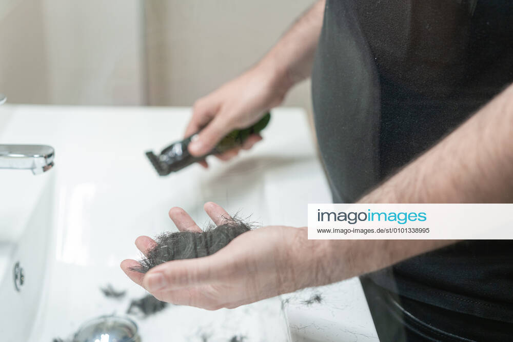 Self haircut. An anonymous man holds strands of hair in the bathroom with his hand Madrid, Community of Madrid, Spain CR_ALSA200429B-372739-01,model released, Symbolfoto