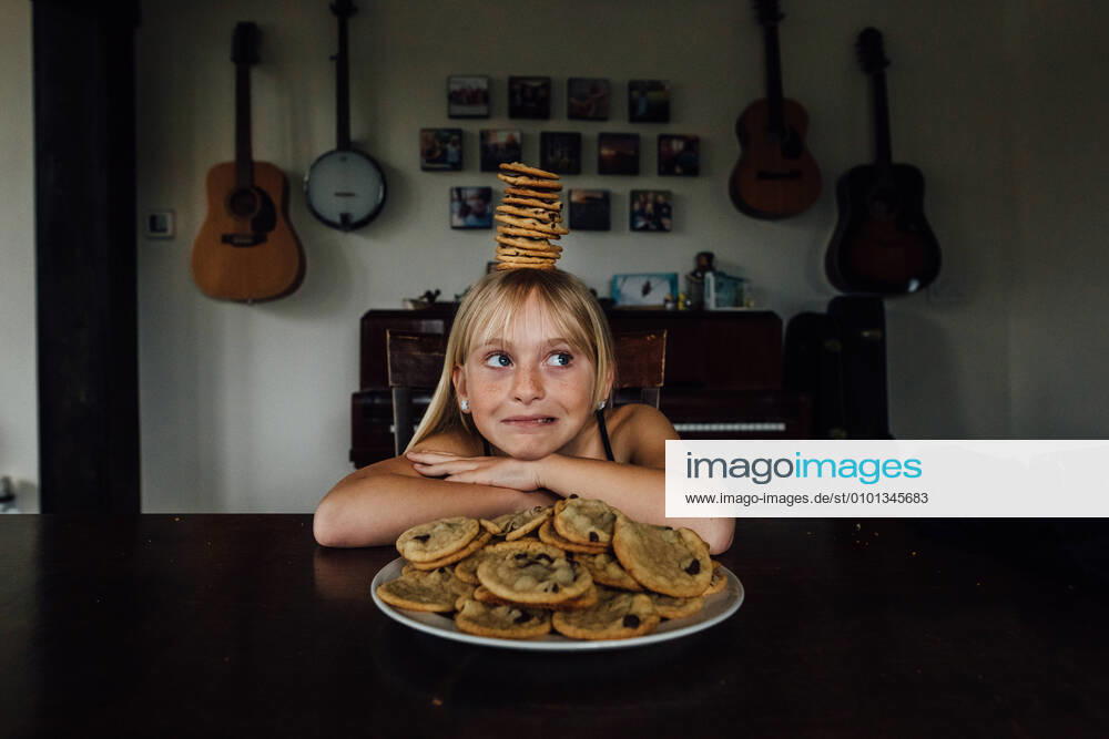 IMAGO Creative: Jahreszeit Winter, Fantasievoll drinnen spielen Young girl balancing cookies on her head Windsor, ON, Canada CR_JEOH200518-377581-01,model released, Symbolfoto