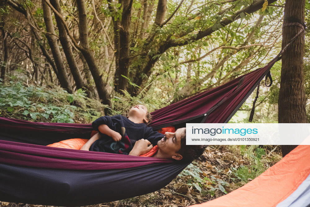 IMAGO Creative: Ende des Sommers A man and a young kid lying in a hammock in the forest Santa Cruz de Tenerife, CN, Spain CR_SEVI200402-201054-01,model released, Symbolfoto