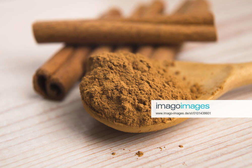 Cinnamon, whole sticks behind wooden spoon with a heap of powder Cinnamon, whole sticks behind wooden spoon with a heap of powder