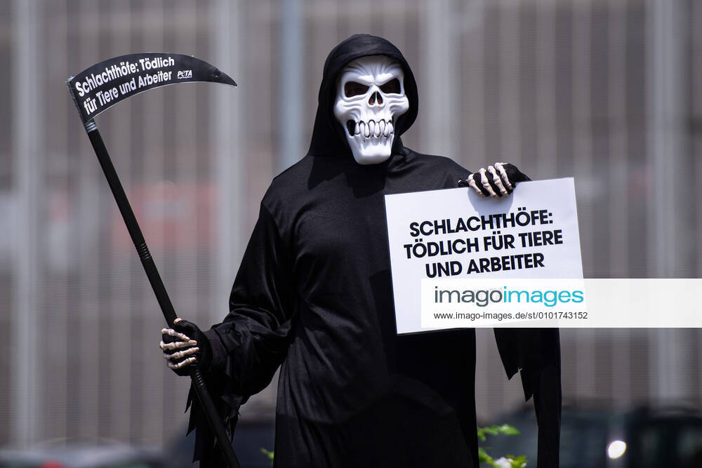 Coronavirus - Demonstration von PETA nach Ausbruch bei Tönnies : Demonstranten der Tierschutzorganisation PETA nach dem Coronavirus Ausbruch bei Tönnies in Rheda-Wiedenbrück, bei dem über 700 Mitarbeiter des Fleischbetriebs positiv auf das Coronavirus getestet wurden, Im Kreis Gütersloh sind daher über 7000 Menschen in Quarantäne. Im Bild: Einer als den Tod verkörperter Demonstrant mit von PETA, der ein Schild gegen Schlachthöfe und Tierquälerei hochhält. Foto: Noah Wedel, Rheda-Wiedenbrück Nordrhein-Westfalen Deutschland