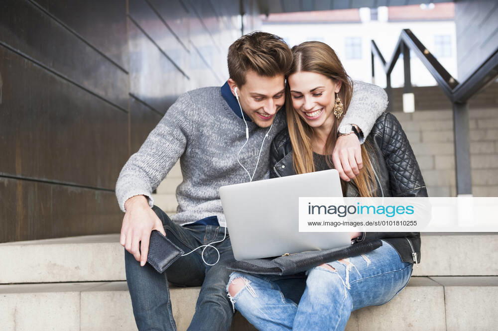 Happy young couple using laptop while sitting on steps in underground walkway model released Symbolfoto DIGF12526