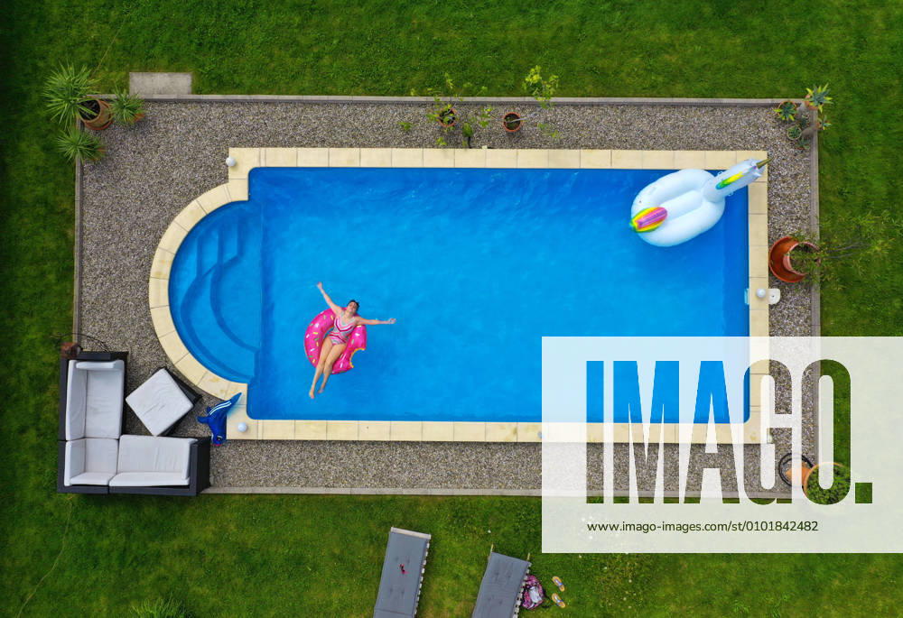 Der eigene Swimmingpool im Garten sorgt im Sommer für Erfrischung wenn die Freibäder geschlossen haben. Luftaufnahme eines Gartenpools im Unterallgäu. Teenager sonnt sich auf einem Schwimmreifen im Wasser. (Modelreleased) 26.06.2020, Swimmingpool im eigenen Garten 26.06.2020, Swimmingpool im eigenen Garten