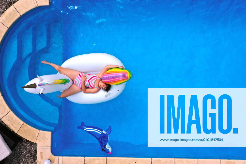 Der eigene Swimmingpool im Garten sorgt im Sommer für Erfrischung wenn die Freibäder geschlossen haben. Luftaufnahme eines Gartenpools im Unterallgäu. Teenager schwimmt im Wasser auf einem Gummi-Einhorn. (Modelreleased) 26.06.2020, Swimmingpool im eigenen Garten 26.06.2020, Swimmingpool im eigenen Garten
