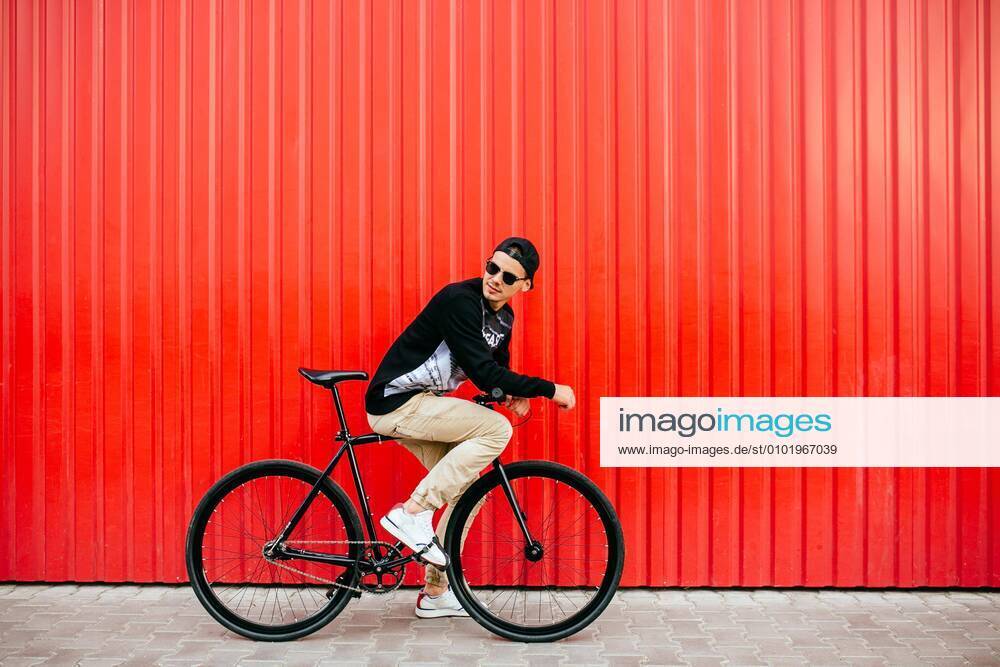 Trendy man sitting on bike, looking back, on the street