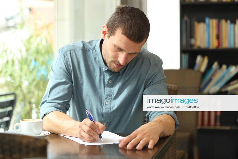 Concentrated man writing notes in a paper in a coffee shop