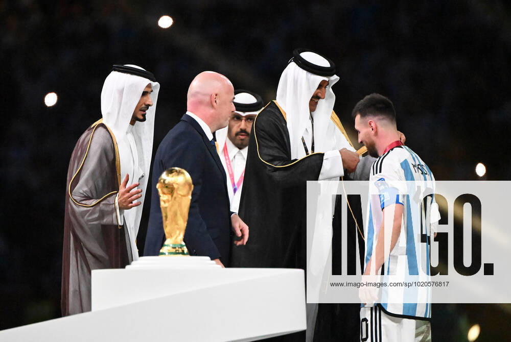 Fussball, Herren, Saison 2022 23, WM in Katar, Finale, Argentinien - Frankreich (2:2, 3:3 n. V, 4:2 i. E.) im Lusail Iconic Stadium in Lusail, v. l. FIFA-Präsident Gianni Infantino, Katars Emir Tamim bin Hamad Al Thani zieht Lionel Messi (Argentinien) bei der Siegerehrung ein Gewand an, 18.12. 2022,