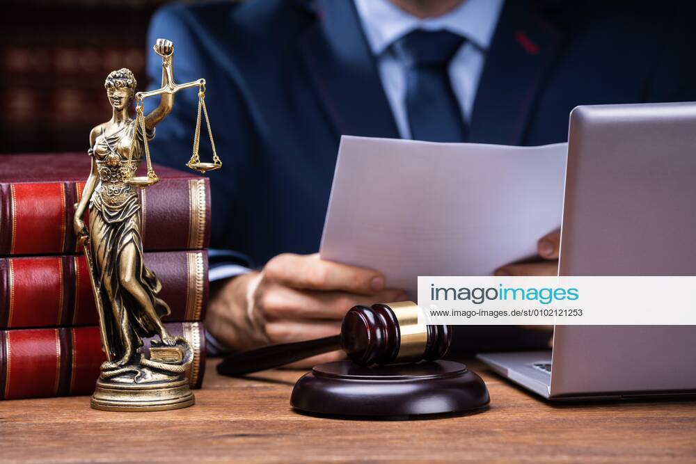 Lawyer Reading Documents Near Mallet And Laptop