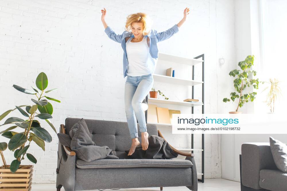 Funny woman jumping on black couch in living room