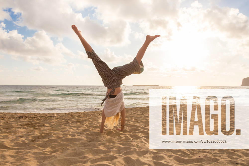 Free Happy Woman Turning Cartwheel Enjoying Sunset on Sandy Beach. Relaxed woman enjoying sun, freedom and life turning cartwheel on beautiful beach in sunset. Young lady feeling free, relaxed and happy. Vacations, freedom, happiness, enjoyment and well being. (License=RF) 10732286