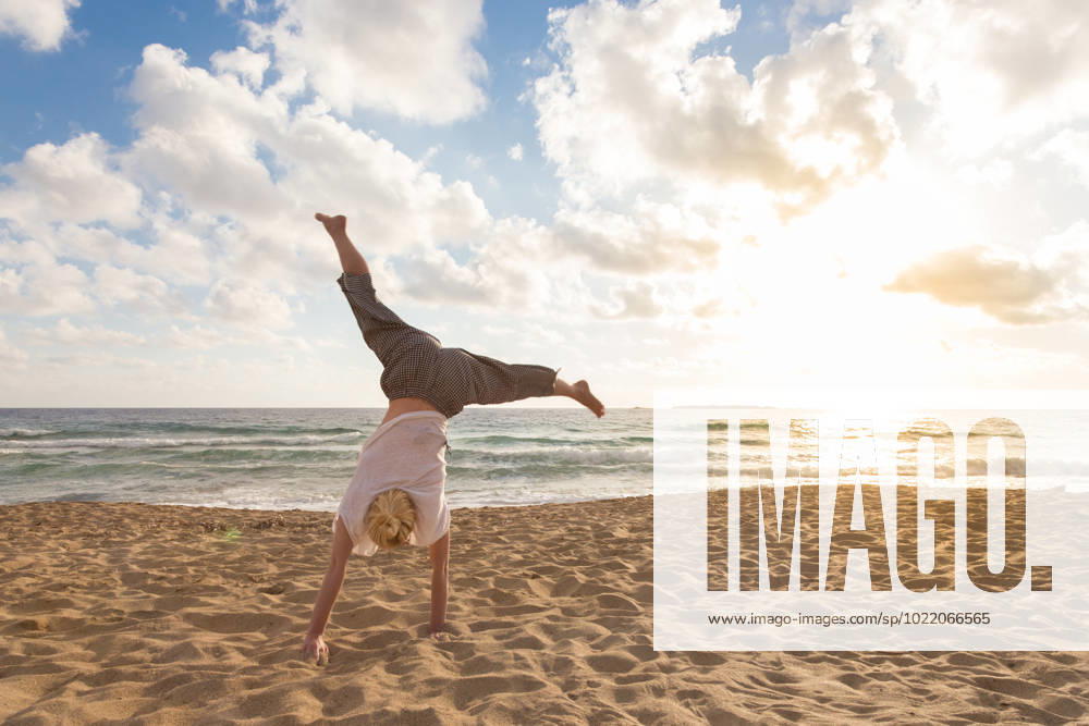 Free Happy Woman Turning Cartwheel Enjoying Sunset on Sandy Beach. Relaxed woman enjoying sun, freedom and life turning cartwheel on beautiful beach in sunset. Young lady feeling free, relaxed and happy. Vacations, freedom, happiness, enjoyment and well being. (License=RF) 10732359