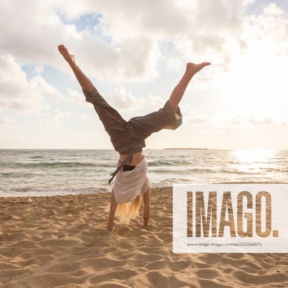 Free Happy Woman Turning Cartwheel Enjoying Sunset on Sandy Beach. Relaxed woman enjoying sun, freedom and life turning cartwheel on beautiful beach in sunset. Young lady feeling free, relaxed and happy. Vacations, freedom, happiness, enjoyment and well being. (License=RF) 10806145