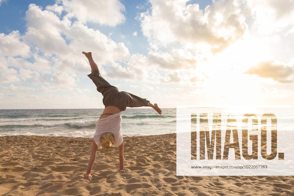 Free Happy Woman Turning Cartwheel Enjoying Sunset on Sandy Beach. Relaxed woman enjoying sun, freedom and life turning cartwheel on beautiful beach in sunset. Young lady feeling free, relaxed and happy. Vacations, freedom, happiness, enjoyment and well being. (License=RF) 10926912
