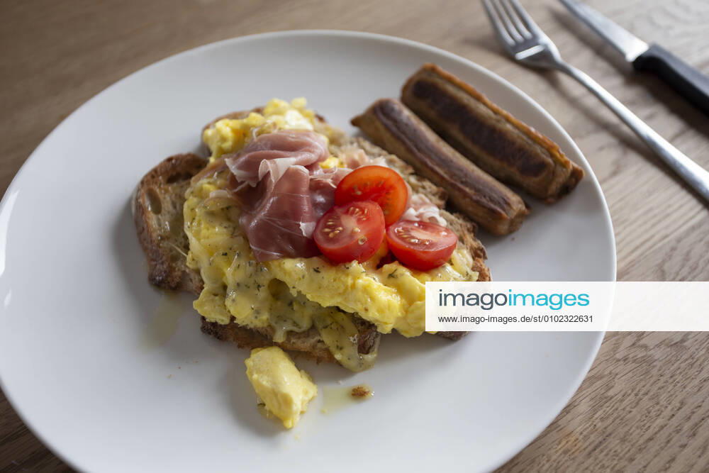 Close up of fresh scrambled eggs on toast with tomato and sausages Zeeland, NB, Netherlands CR_GAWA200701-425607-01