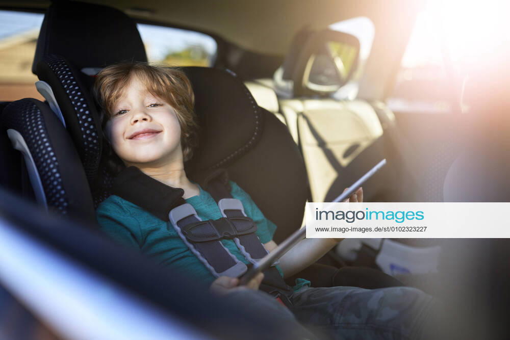 Portrait of smiling boy using digital tablet while sitting at back seat in car Los Angeles, CA, United States CR_JAJEES200707-446920-01 ,model released, Symbolfoto