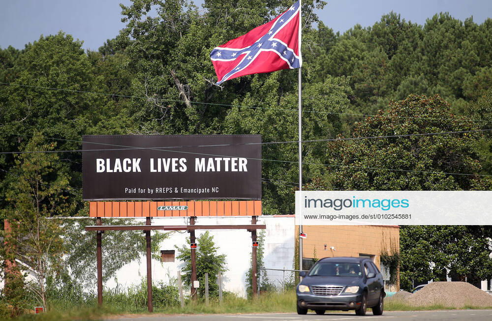 Pittsboro, North Carolina, USA - A Black Lives Matter billboard stands next to Confederate flag on US Highway 64 Thursday. An online fundraiser helped pay for the billboard near where a controversial Confederate statue was removed last year. The billboard, which will be up for a year, features the words Black Lives Matter and was paid for by RREPS & Emancipate NC. After months of sometimes violent protests, officials in November removed a Confederate statue that had stood in front of the Chatham County Courthouse for more than a century. PITTSBORO USA - ZUMAk251 20200717_new_k251_013