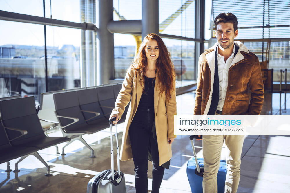 Confident business couple standing with luggage at airport departure area model released Symbolfoto EHF00444