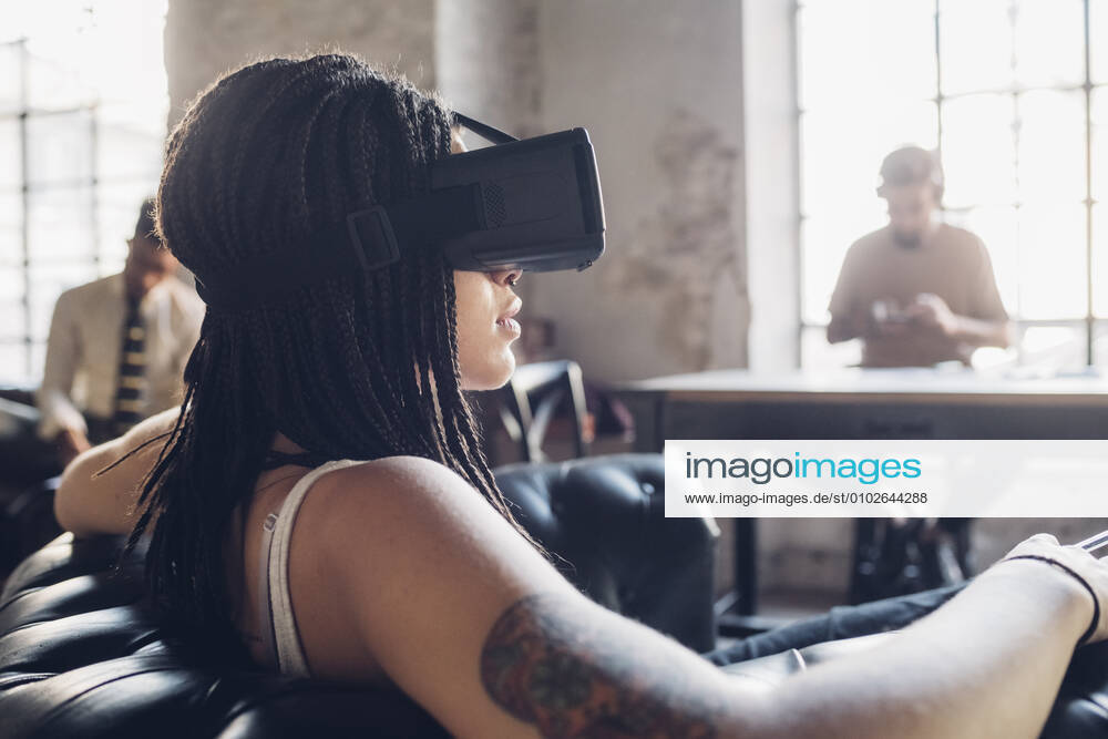Young woman relaxing in armchair in loft office wearing Vr goggles model released Symbolfoto property released MEUF00736