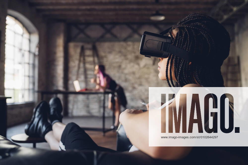 Young woman relaxing in armchair in loft office wearing Vr goggles model released Symbolfoto property released MEUF00740