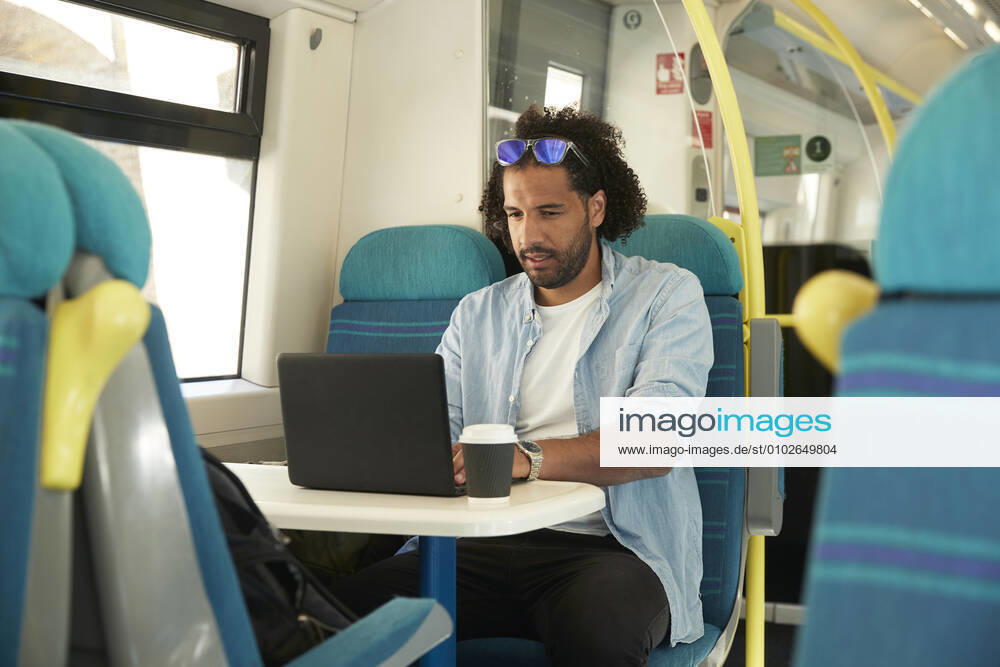 Young trendy man using laptop in train model released Symbolfoto PMF01108