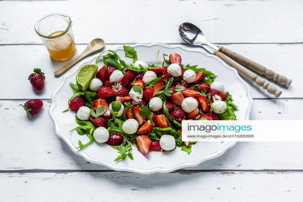 Plate of vegetarian summer salad with lime, arugula, strawberries, mozzarella, mint and daisies SARF04598