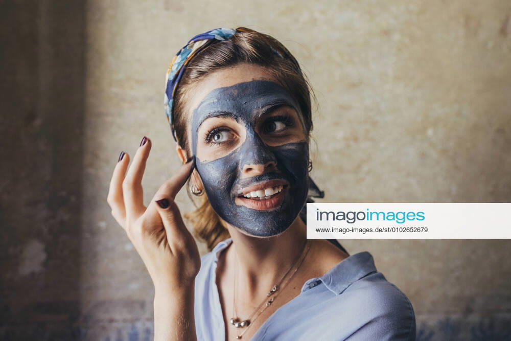 Close-up of young woman applying facial mask while looking away at home model released Symbolfoto property released SBAF00020