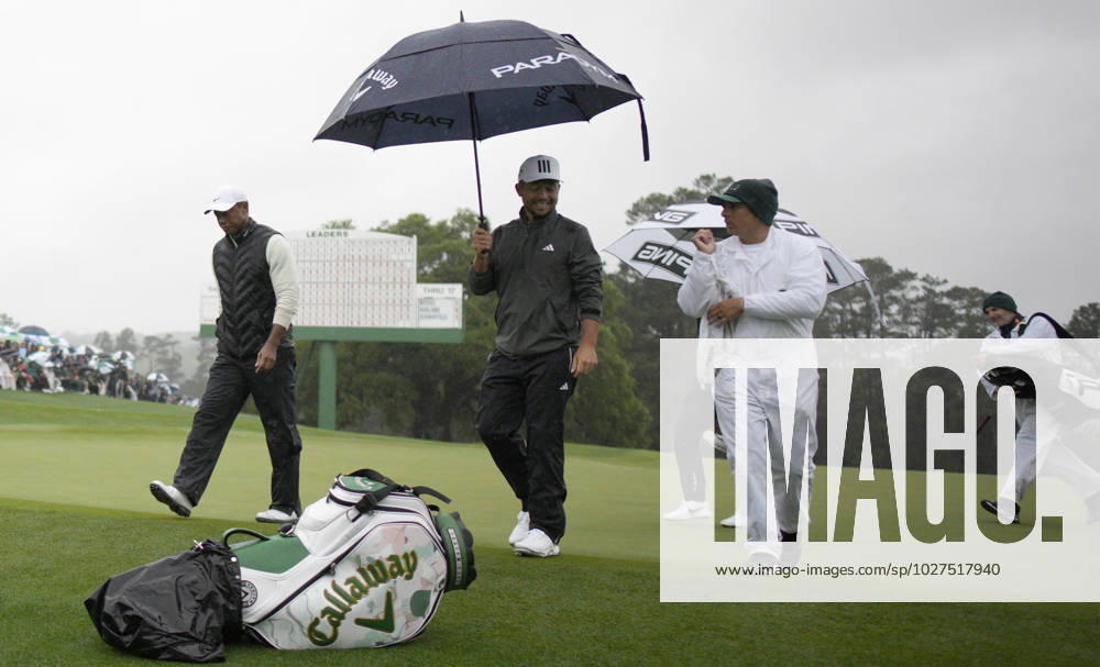 Tiger Woods (L) and Xander Schauffele (C) leave the 18th green after completing the rain delayed second round at the 87th Masters tournament at Augusta National Golf Club in Augusta, Georgia on Saturday, April 8, 2023. Woods made the cut finishing at 147. Schauffele finished at 142. AUG20230408223 BOBxSTRONG