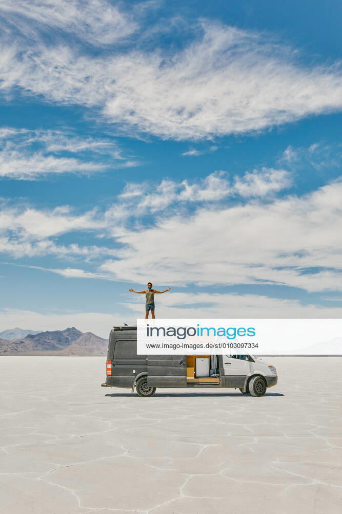 Young man standing on roof of camper van in Bonneville Salt Flats. Salt Lake City, UT, United States CR_JUSLKY200806-466993-01 ,model released, Symbolfoto ,property released