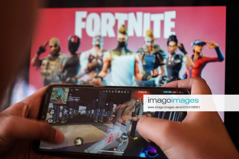 A child is playing a game on a cellphone with a picture of the Fortnite game on the computer screen in the background. Apple and Google announced their decision to remove Fortnite games from the App Store and Google Play app stores. Makassar Indonesia - ZUMAb223 20200815_zip_b223_003