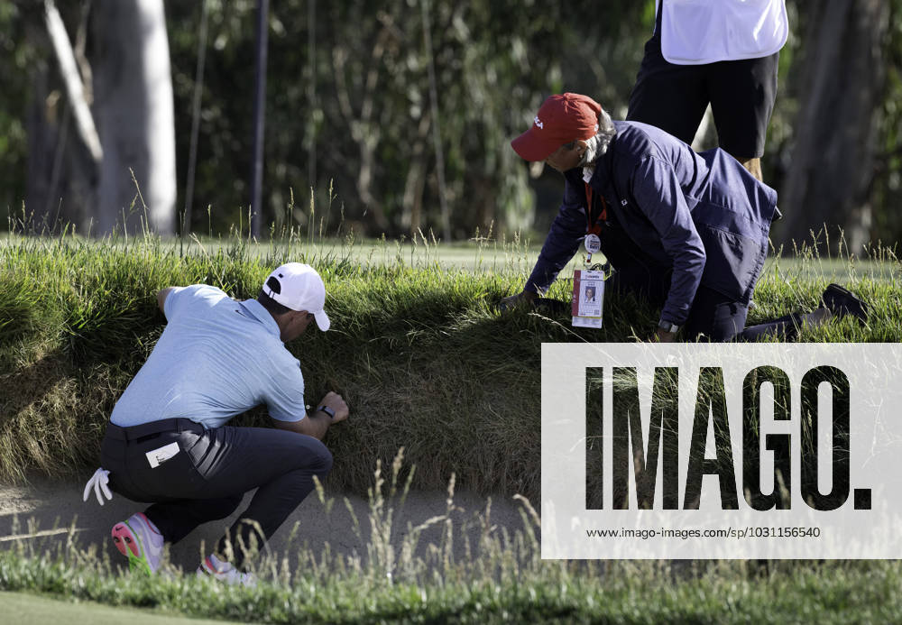 Golfer Rory Mcllroy locates his ball in the rough just above a greenside bunker on the 14th hole during the 4th round of the US Open on June 18, 2023. The official next to Mcllroy allowed him to have a free drop. Los Angeles USA - ZUMAh234 20230618_zsp_h234_020