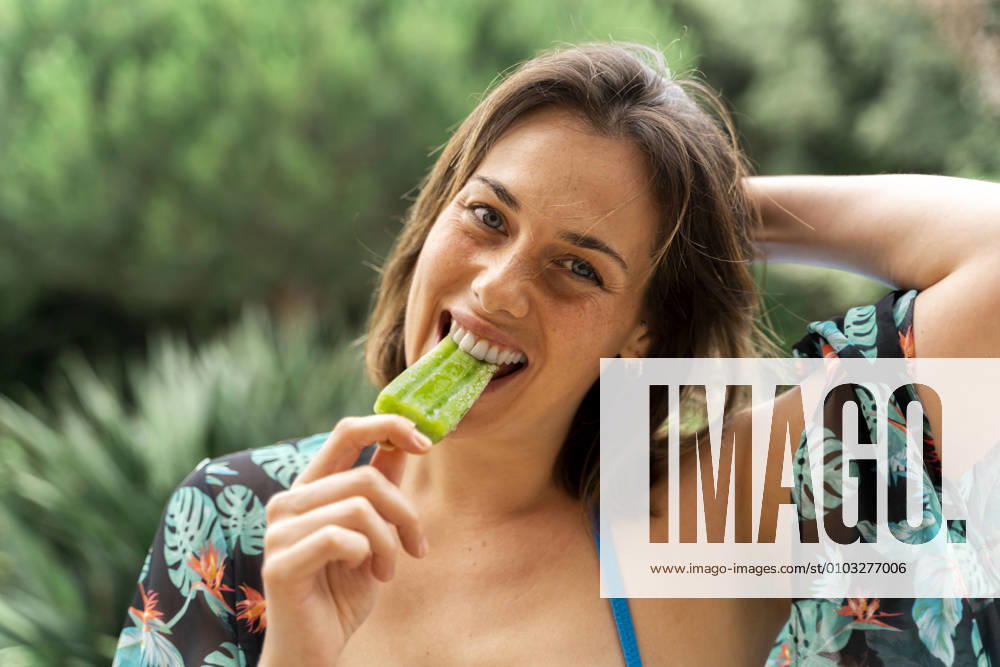 Happy young woman eating popsicle at yard model released Symbolfoto AFVF06813