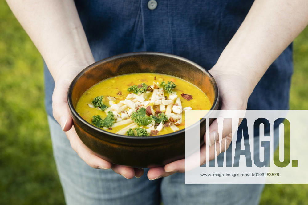 Mans hands holding bowl with dal of lentils, potatoes and vegetables model released Symbolfoto EVGF03632