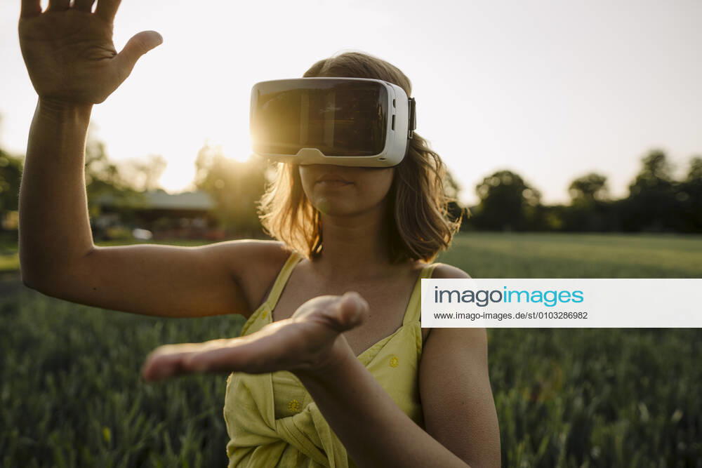 Young woman wearing VR goggles in a grain field in the countryside model released Symbolfoto property released GUSF04281