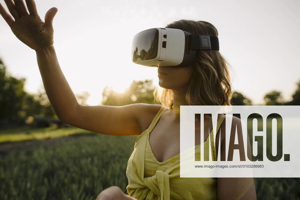 Young woman wearing VR goggles in a grain field in the countryside model released Symbolfoto property released GUSF04282