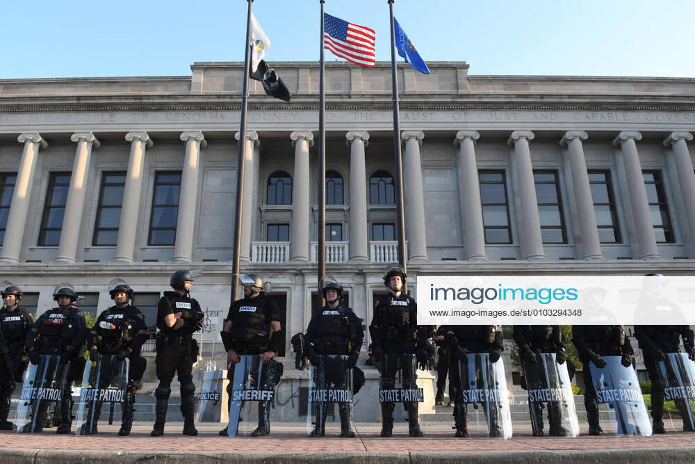 The Kenosha County Court House in downtown Kenosha, Wisconsin is guarded by a phalanx of city police, sheriffâ€⠢s deputies, and Wisconsin State Patrol officers early Monday August 24, 2020 after the shooting of Jacob Blake, an African-American man, by a white police officer the day before. Video shows the officer grabbing Blake by his t-shirt from behind as he tried to get in his car, and then shooting him seven times in the back at pointblank range. The shooting, which was condemned by Wisconsin Gov. Tony Evers, was followed by fires and looting downtown. Blake is reported Monday out of surgery and in intensive care. Kenosha USA - ZUMAh154 20200824_znp_h154_014