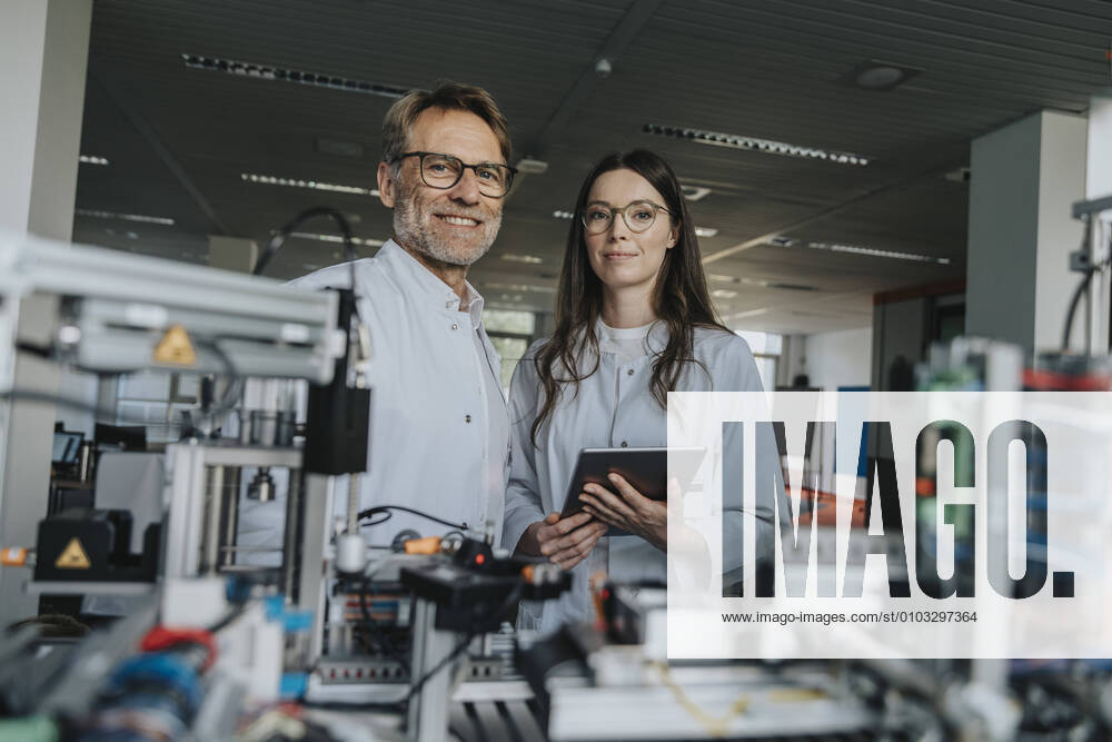 IMAGO Creative: Business, Innovative Technologie-Lösungen Confident scientists standing by machinery in laboratory model released Symbolfoto property released MFF05902